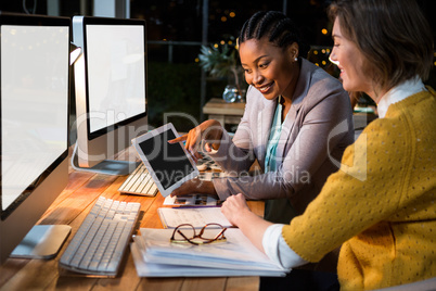 Businesswoman discussing with colleague over digital tablet