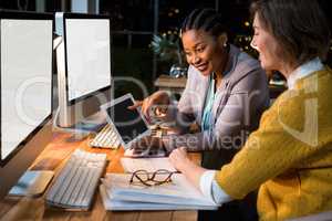 Businesswoman discussing with colleague over digital tablet