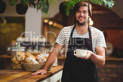 Portrait of waiter offering a cup of coffee