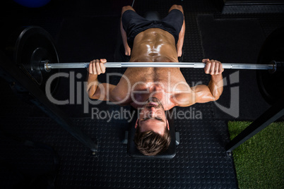 Shirtless determined man exercising with barbell