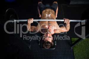Shirtless determined man exercising with barbell