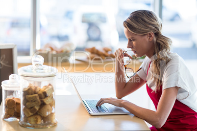 Waitress sitting at table and using laptop