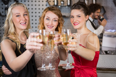 Three smiling friend showing glass of champagne