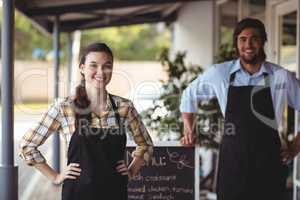 Waiter and waitress standing with menu board outside the cafe