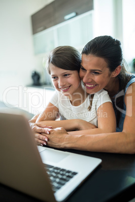 Mother and daughter using laptop and digital tablet in the living room