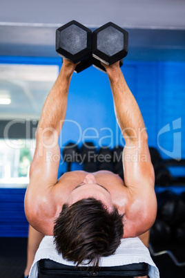 Shirtless man lifting dumbbell