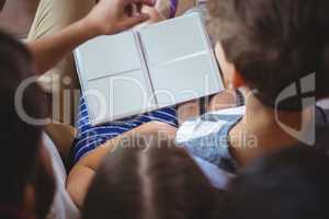 Rear view of siblings looking at a photo album