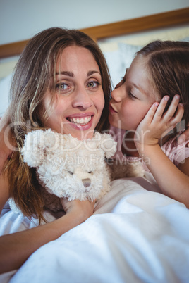 Daughter kissing mother on bed