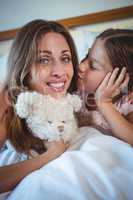 Daughter kissing mother on bed