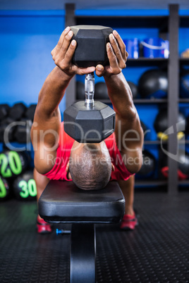 Man exercising with dumbbell on bench