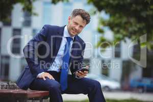 Portrait of handsome businessman holding mobile phone