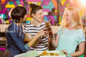 Three female friends toasting bottle of beer