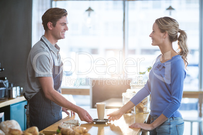 Waiter serving a cup of cold coffee to customer at counter