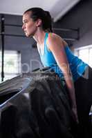 Female athlete pushing tire in gym