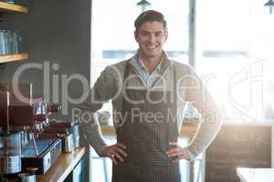 Smiling waiter standing with hand on hip in cafÃ?Â©
