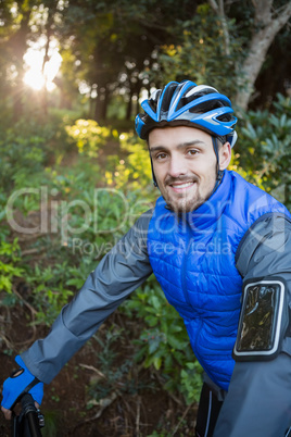 Portrait of male mountain biker with bicycle in the forest