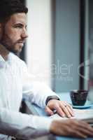 Businessman sitting at table and reading newspaper in office