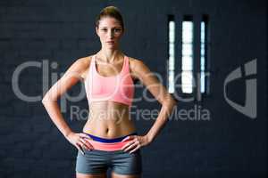 Portrait of fit young woman with hands on hip in gym