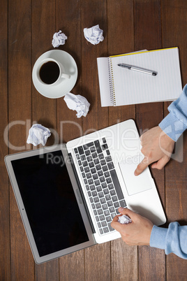 Man using laptop while writing on notepad