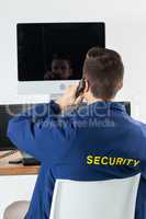 Security officer talking on telephone while looking at computer monitors