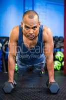 Portrait of serious male athlete doing push-ups with dumbbells