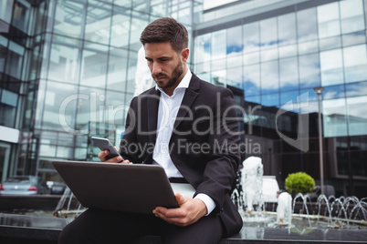 Businessman using mobile phone and laptop