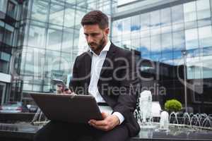 Businessman using mobile phone and laptop