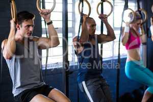 People hanging from gymnastic rings in gym