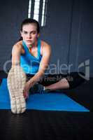 Portrait of young woman stretching in gym