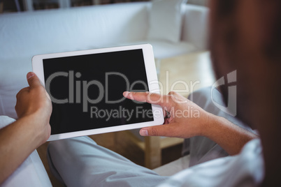 Mid section of man using digital tablet in living room