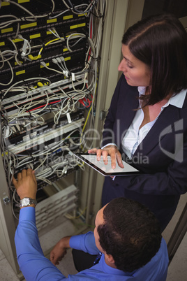 Technicians using digital tablet while analyzing server