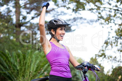 Female cyclist standing with mountain bike in park