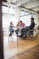 Businessman on wheelchair with photo editors in meeting room
