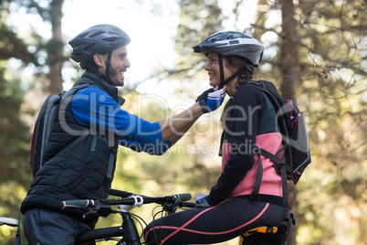 Man adjusting bicycle helmet of a woman