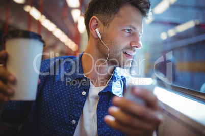 Handsome man listening music on mobile phone while having coffee