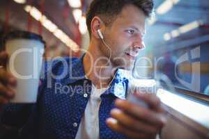 Handsome man listening music on mobile phone while having coffee