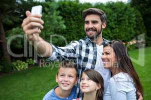 Happy family taking a selfie from mobile phone in park