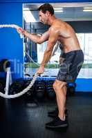 Shirtless athlete holding rope in gym