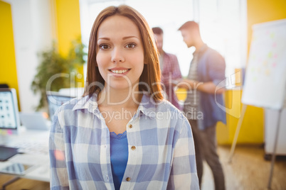 Smiling businesswoman standing against coworkers