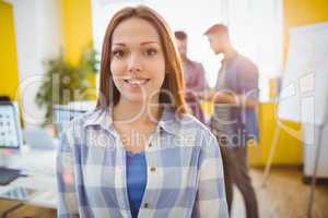 Smiling businesswoman standing against coworkers
