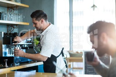 Smiling waiter making cup of coffee