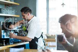 Smiling waiter making cup of coffee