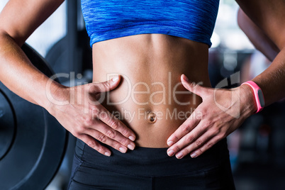 Midsection of athlete touching belly in gym