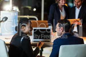 Businesspeople discussing over laptop and digital tablet