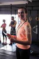 Portrait of happy female fitness instructor holding clipboard in gym