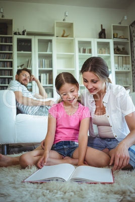Mother and daughter sitting on the floor and looking at photo album