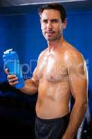 Portrait of shirtless athlete holding water bottle