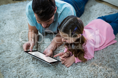 Father and daughter using digital tablet in the living room