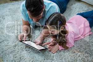 Father and daughter using digital tablet in the living room