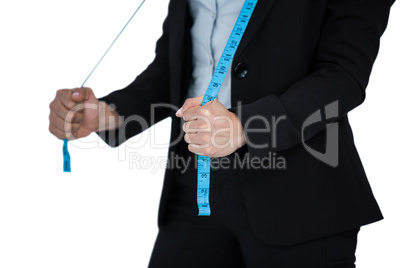 Businesswoman holding a measuring tape against white background